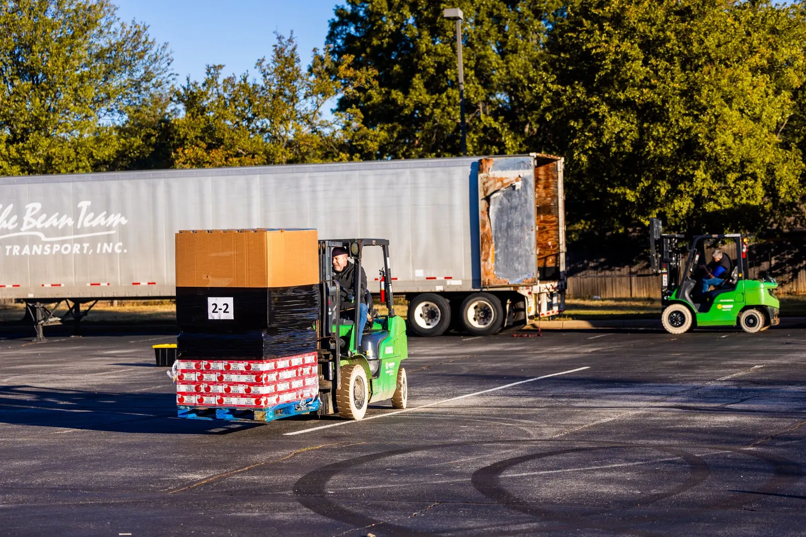 Forklift operators loading pallets onto a freight truck
